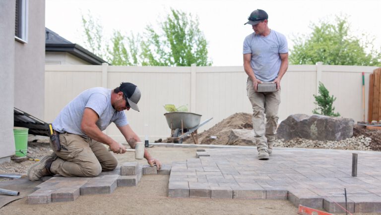 Hardscape crew installing pavers on a screeded sand bed in a Treasure Valley backyard