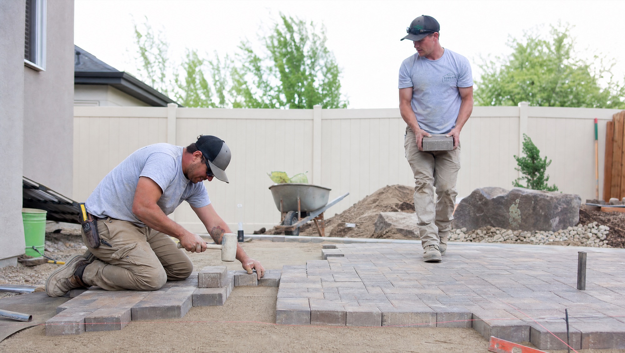 Hardscape crew installing pavers on a screeded sand bed in a Treasure Valley backyard